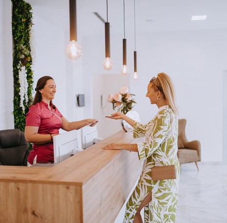 Dental receptionist assists client at desk?