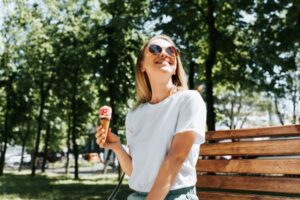 a woman sitting on a park bench and eating ice cream